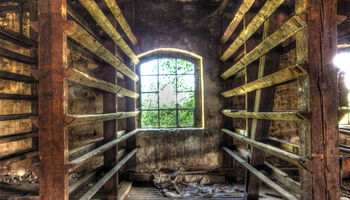 Verfallene Holzhalle mit Fenster und Regalen.